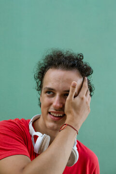Portrait of a young man. Playful young man covering one eye with hand and smiling.