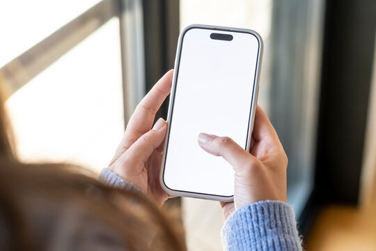 Person is holding a modern smartphone with a blank white screen in hands, using a finger to scroll, representing concepts of communication, technology, and interaction