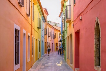 Fototapeta premium Rue étroite bordée de façades multicolores, architecture traditionnelle colorée, destination touristique pittoresque et ambiance méditerranéenne ensoleillée
