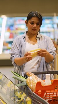 Woman buying cheese and groceries in a modern supermarket