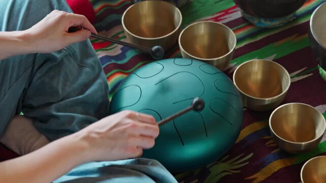 Women's hands playing on a  hang pad make a musical ceremony in a gazebo.
