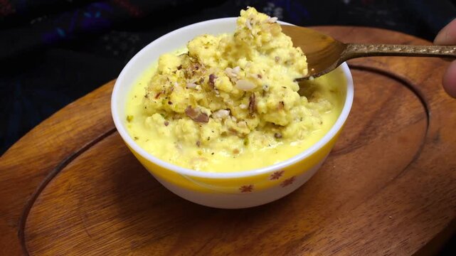 creamy homemade kesar kheer being scooped and lifted with a spoon, showcasing its rich saffron color and smooth texture as a traditional Indian dessert.