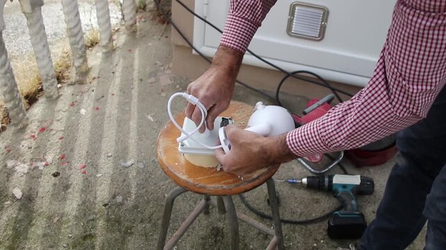 Professional electrician feeds CCTV camera cables into a junction box while preparing a surveillance system installation.
