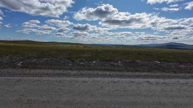 POV driving across Flatruet mountain plateau in Sweden. First-person view on a scenic gravel road through vast highland landscapes with mountains, tundra and open wilderness.