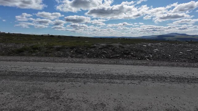 POV driving across Flatruet mountain plateau in Sweden. First-person view on a scenic gravel road through vast highland landscapes with mountains, tundra and open wilderness.