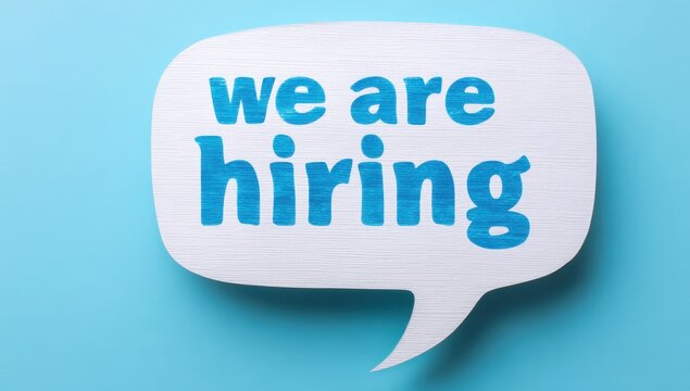 We are hiring sign on textured paper speech bubble on blue surface with employment recruitment business corporate announcement opportunity staffing resources personnel recruiting