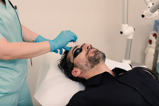 Specialist applies liquid to man's forehead during a facial procedure.