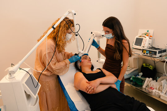 Cosmetic dermatologists perform a laser facial procedure.
