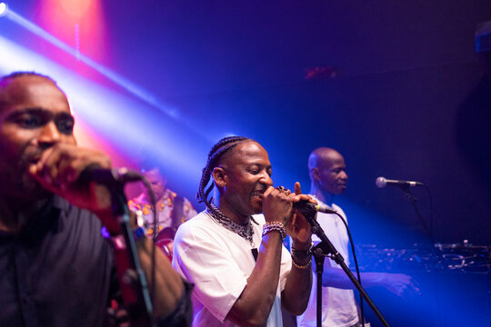 Black musicians performing live concert with bright stage lighting