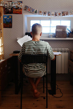 Teenager studying at desk in bedroom from behind