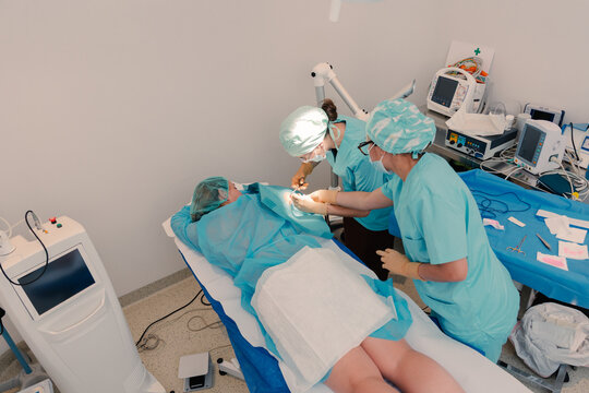 Derm in scrub performs clinical procedure with advanced medical tools