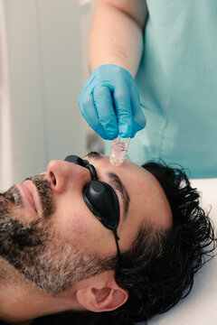 Dermatologist applies treatment to man's forehead during a procedure.