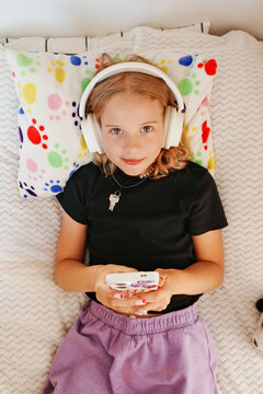 Young person playing video games with headphones on bed