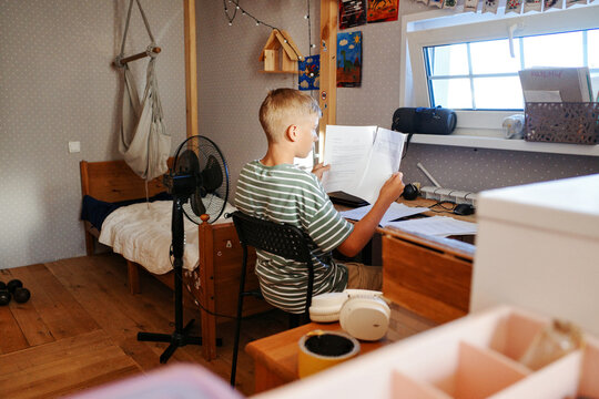 Teenager studying with papers at desk in bedroom