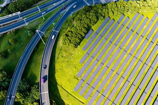 Traffic road beside solar panels in green landscape