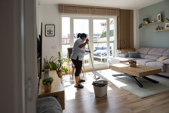 Housekeeper mopping living room floor for professional cleaning