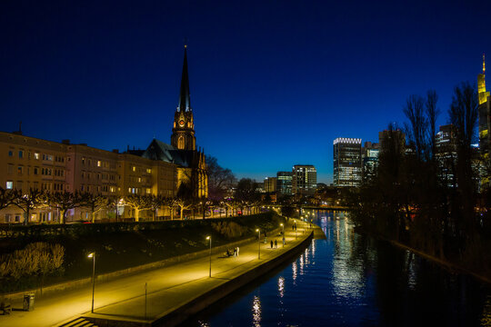 Frankfurt, Germany, view of the illuminated banks of the Main river with the Dreikoenigskirche after sunset during the blue hour