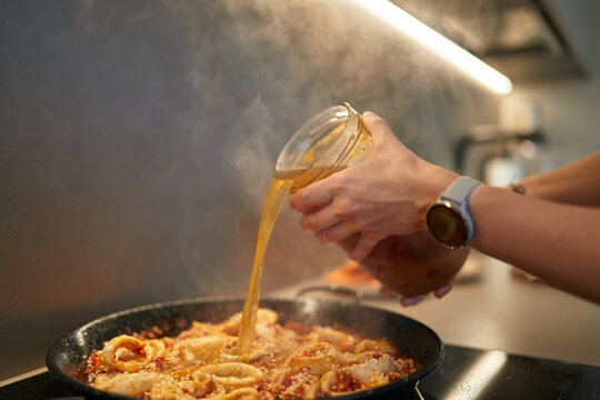Pouring Broth into Steaming Seafood Paella