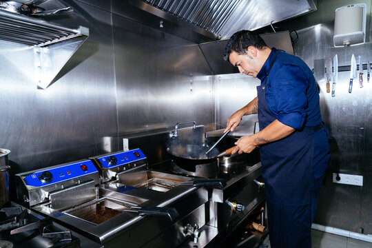 Professional chef working in busy restaurant kitchen, preparing food