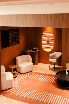 Modern clinic waiting room with wood walls, armchairs, and lit shelf.