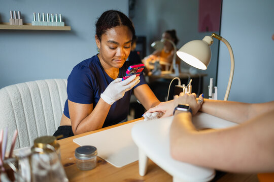 Nail artist photographing her manicure work on a client's nails
