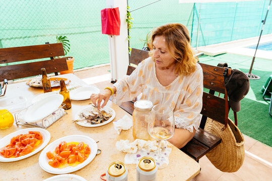 Woman enjoying outdoor lunch with grilled fish and tomatoes