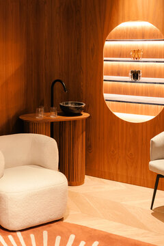 Clinic with wood walls, lit shelf, dark sink, beige chairs, and rug.