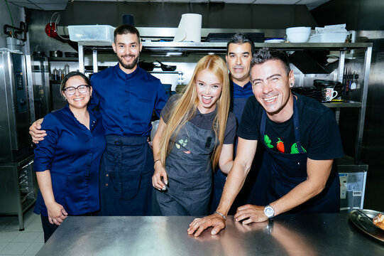 Happy professional chef group smiling in restaurant kitchen