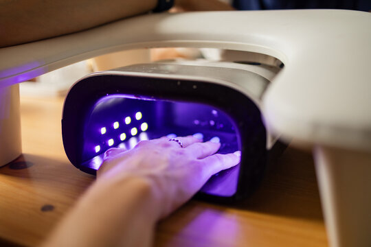 Hand curing under a UV LED nail lamp during a gel manicure