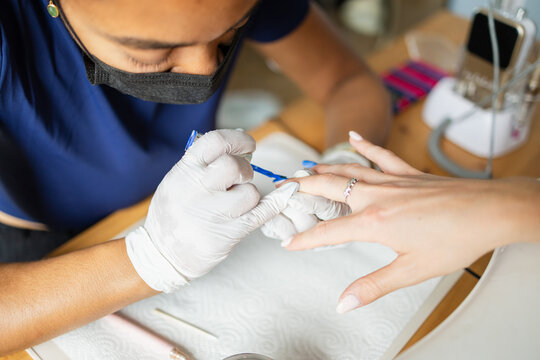 Nail technician applying blue nail polish