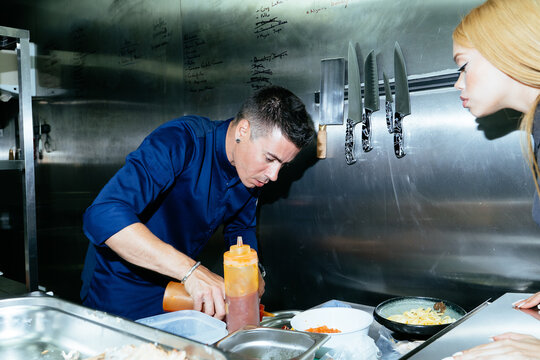 Chef skillfully preparing food with sauce in commercial kitchen