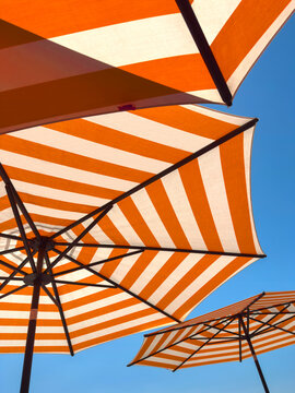Orange and wite stripes sun umbrellas closeup detail and blue sky