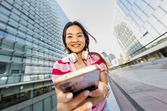 Smiling woman using smartphone looking at camera 
