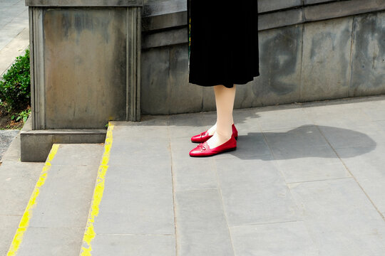 Woman wearing red shoes standing near outdoor steps