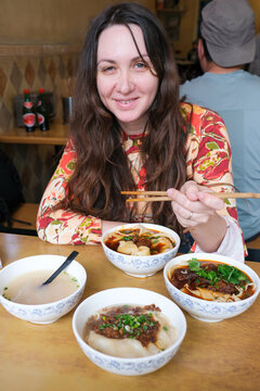 Woman enjoying traditional Chinese noodles at a local restaurant
