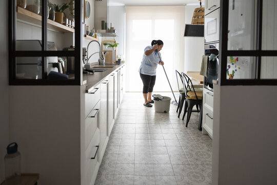 Housekeeper mopping kitchen floor in domestic service