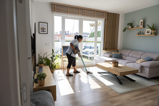 Housekeeper vacuuming living room floor for cleanliness
