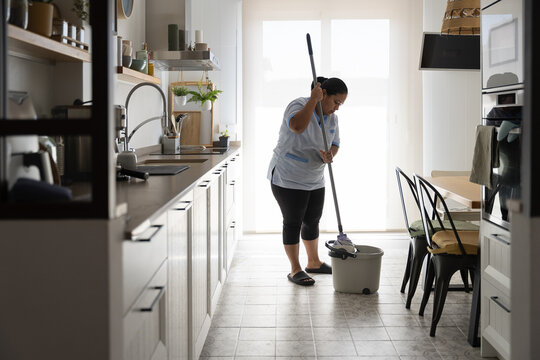Housekeeper mopping kitchen floor for home cleaning service