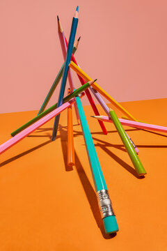 Colored Pencils Balanced in Abstract Arrangement on Orange Background