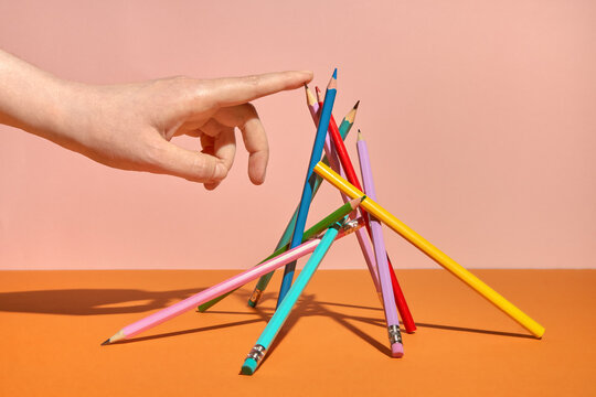 Still life with Hand and Balanced Pencils on Orange Background
