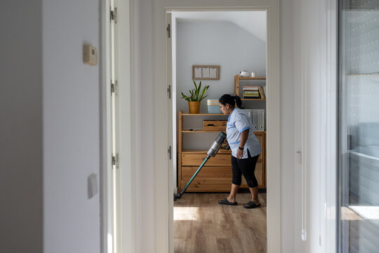 Housekeeper vacuuming floor for clean home service