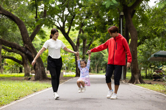 Parents are here reate perfect day for childrent. Father and mother hands and raise her up and walk. exercising and walking together in city park summer. healthy lifestyle in nature. family bonding