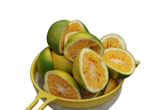 Una toma de cerca de varias naranjas cortadas dentro de un colador amarillo para hacer jugo de naranja en un fondo transparente 