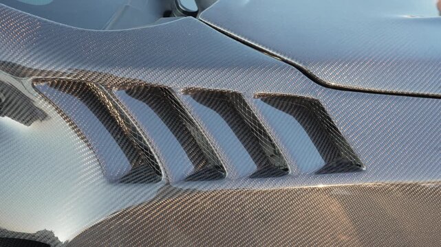 Close-up of a carbon fiber car fender with air vents.