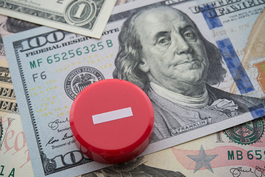 Minus symbol on US dollar banknotes background. Central banking system of the United States FED (Federal Reserve System) cut interest rate to control inflation, world finance and economy concept.