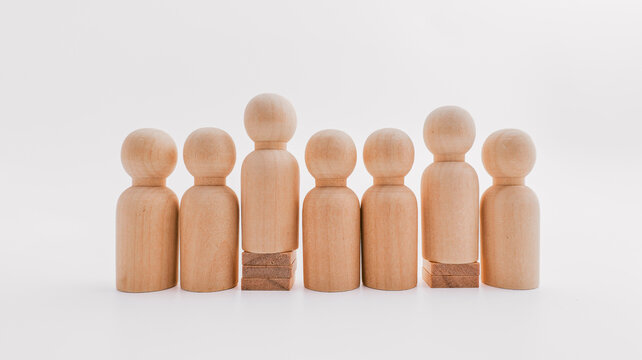 Group of wooden peg people standing together on a white background