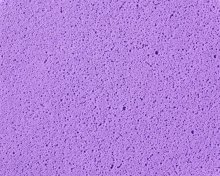 purple sponge texture background, porous foam surface with tiny bubbles and holes, macro close-up view, abstract cleaning material