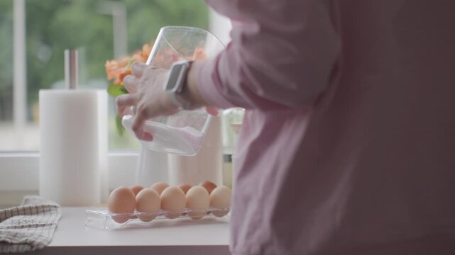 Woman opens glass jar, adds salt and closes it near eggs on kitchen counter. Concept of baking ingredients and food preparation