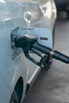 car diesel fuel nozzle inserted in vehicle tank closeup black dispenser held by person in blue shirt fueling at gas station service concept of automotive transport energy industry