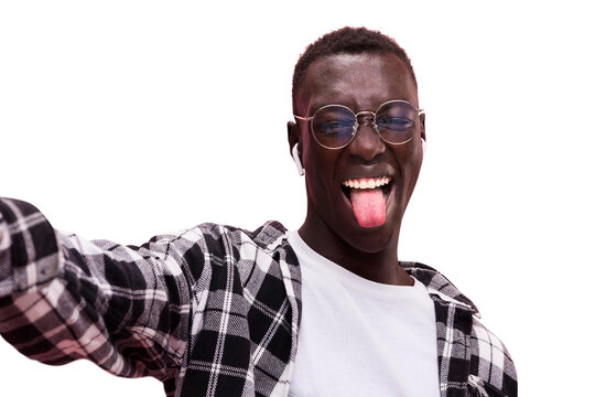 Joyful young black man wearing glasses taking a selfie while sticking out his tongue on isolated white background